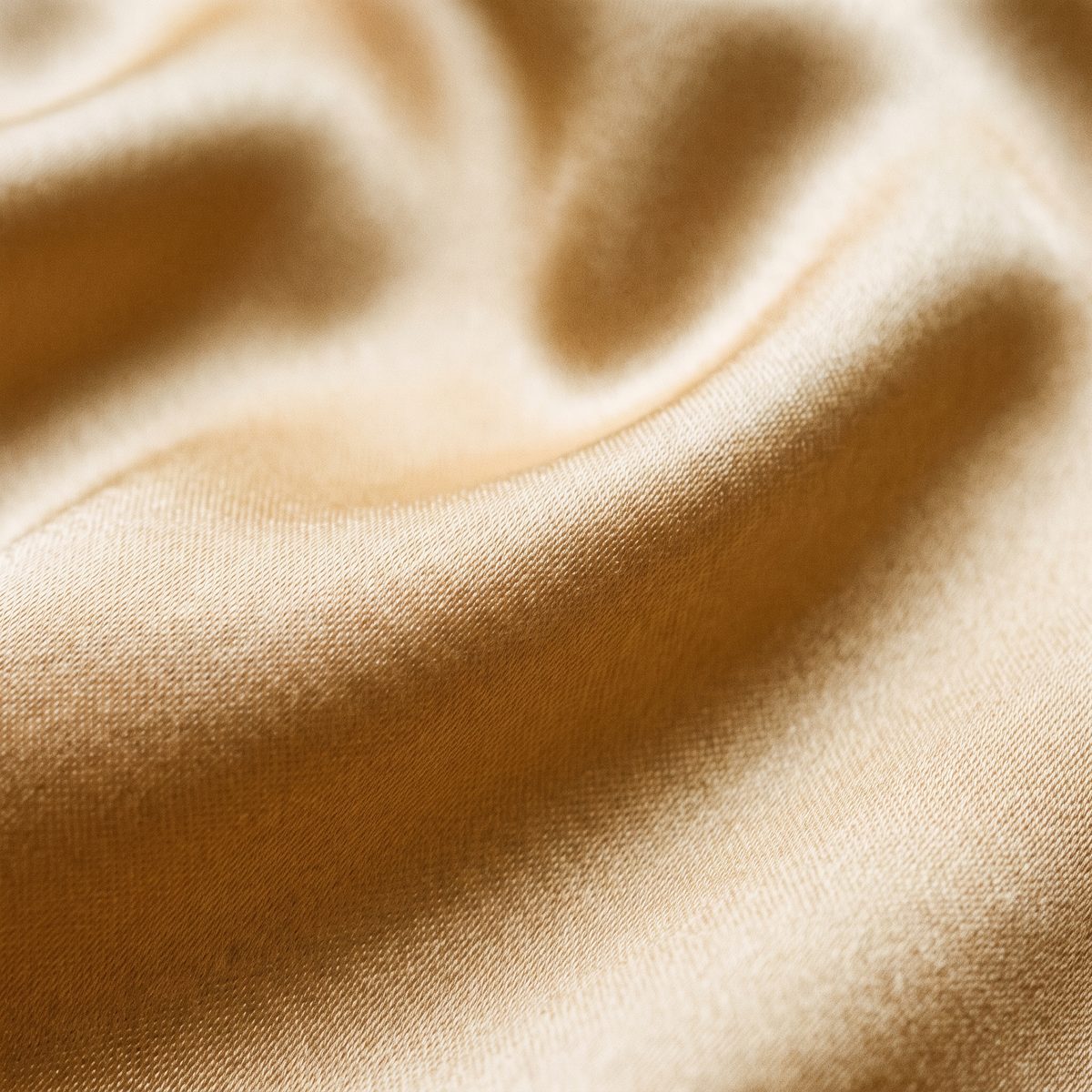 A close study of golden silk, showing the weight and fall of the cloth